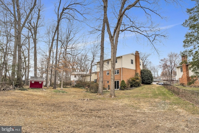 view of yard featuring an outbuilding, a storage shed, and fence