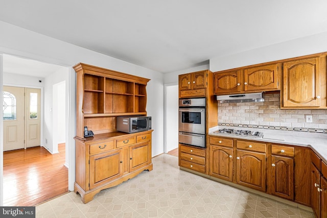 kitchen featuring a warming drawer, brown cabinets, open shelves, tasteful backsplash, and appliances with stainless steel finishes