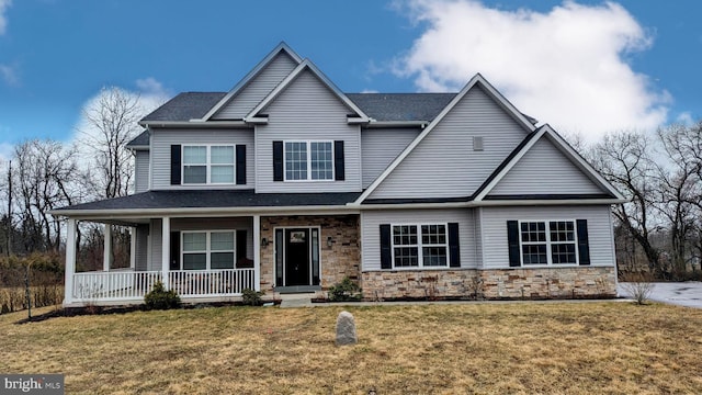 view of front of home featuring stone siding, a shingled roof, a porch, and a front lawn