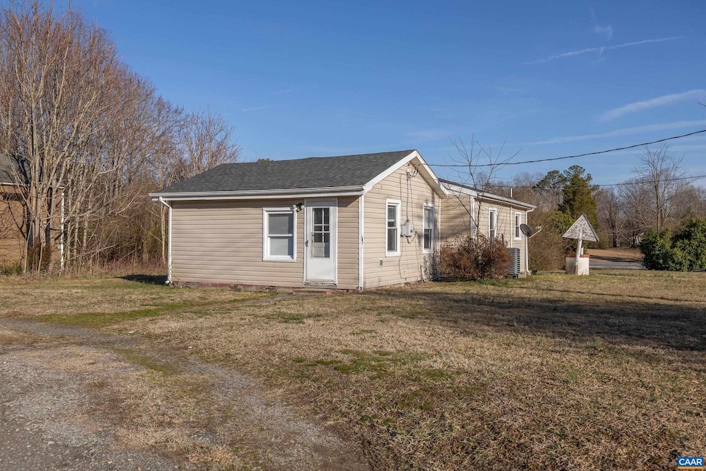 view of side of property featuring a yard and roof with shingles