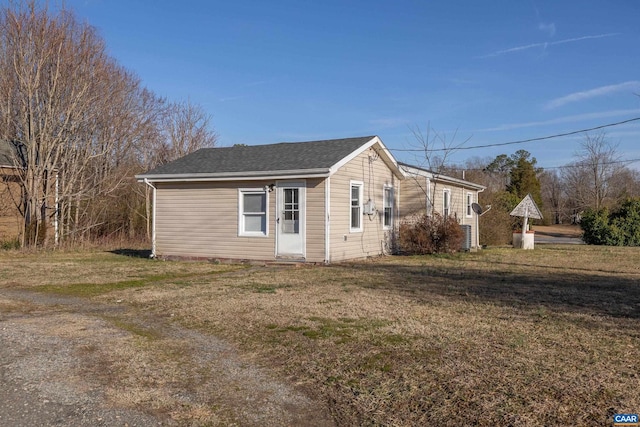 view of side of property featuring a yard and roof with shingles