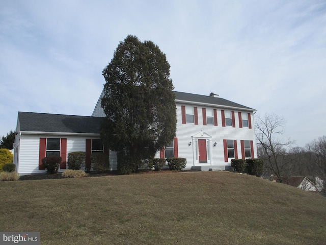 colonial-style house featuring a front lawn