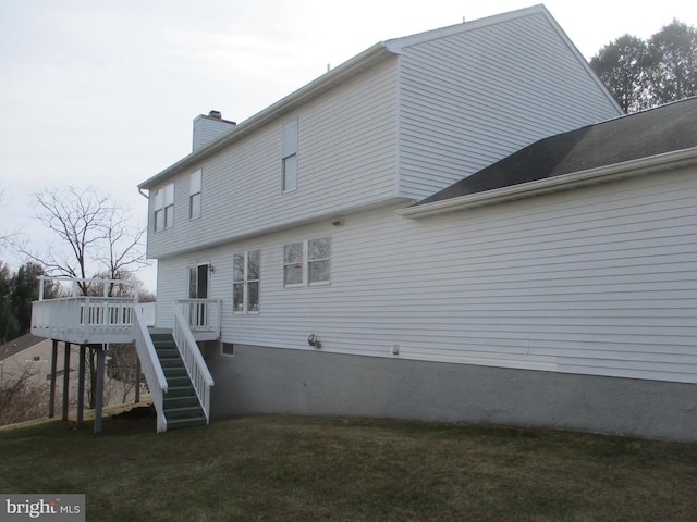 rear view of property with a chimney, a yard, stairway, and a wooden deck