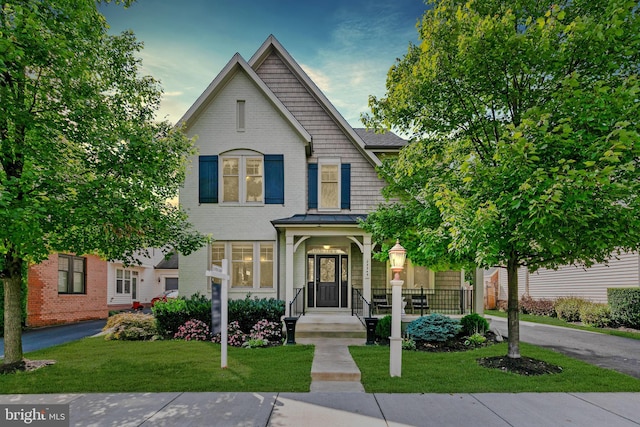 view of front of home featuring brick siding, a standing seam roof, and a front yard