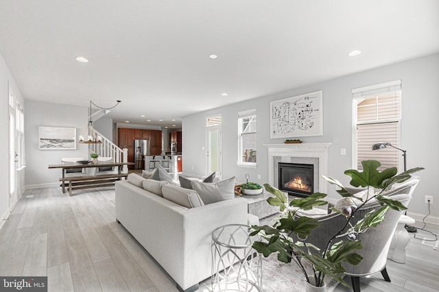 living room with stairs, a high end fireplace, light wood-style flooring, and recessed lighting