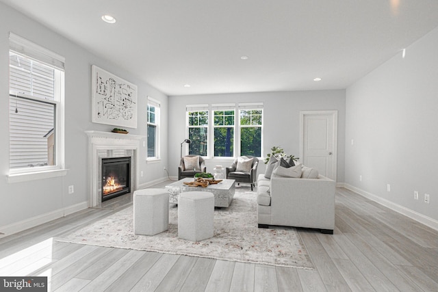 living room featuring light wood-type flooring, a fireplace, baseboards, and recessed lighting