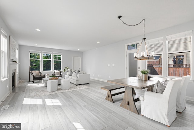 living area with light wood-style floors, a fireplace, recessed lighting, and a notable chandelier