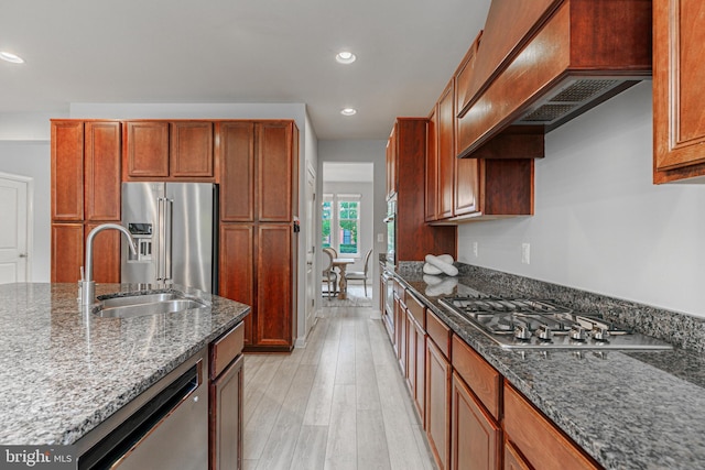 kitchen featuring appliances with stainless steel finishes, dark stone countertops, a sink, and custom exhaust hood