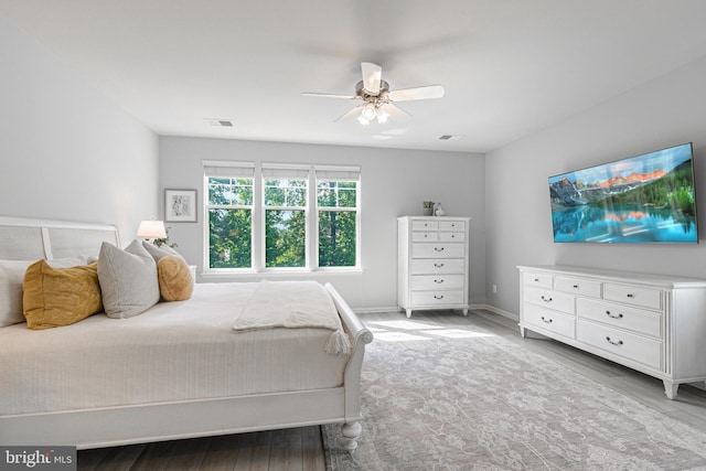 bedroom with baseboards, visible vents, ceiling fan, and wood finished floors