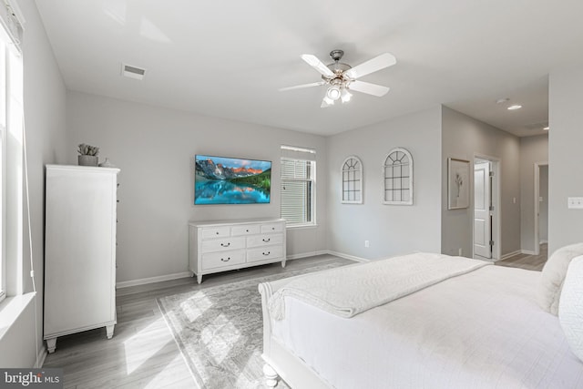 bedroom featuring a ceiling fan, baseboards, visible vents, and wood finished floors