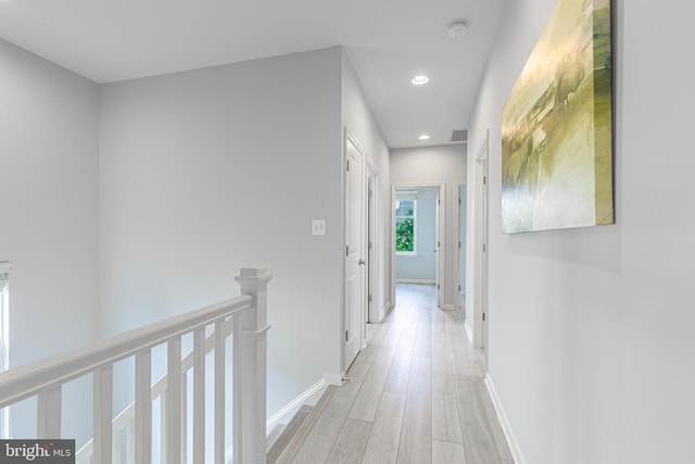 corridor featuring recessed lighting, light wood-type flooring, an upstairs landing, and baseboards