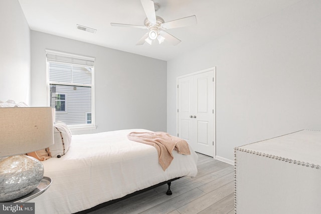 bedroom featuring a ceiling fan, baseboards, visible vents, light wood-style floors, and a closet