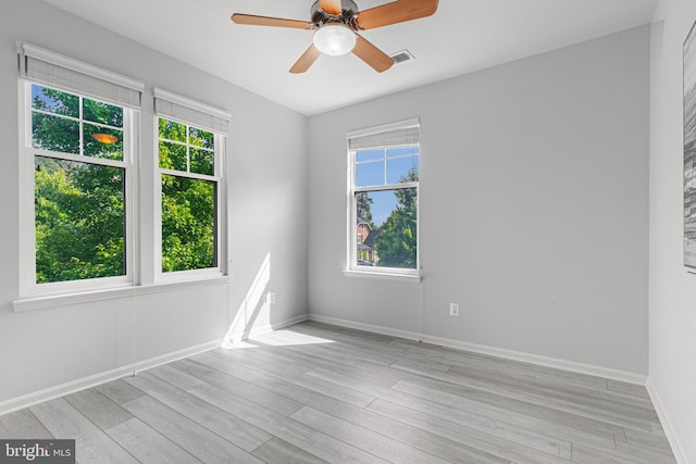 empty room with ceiling fan, light wood-type flooring, visible vents, and baseboards