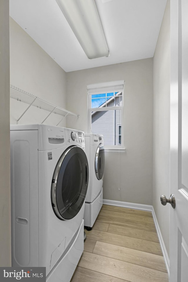 laundry room featuring laundry area, baseboards, light wood finished floors, and washing machine and clothes dryer