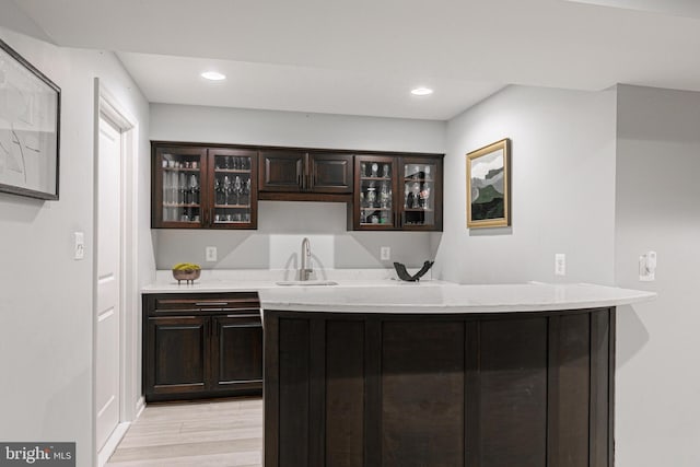 bar featuring light wood-style flooring, wet bar, a sink, and recessed lighting