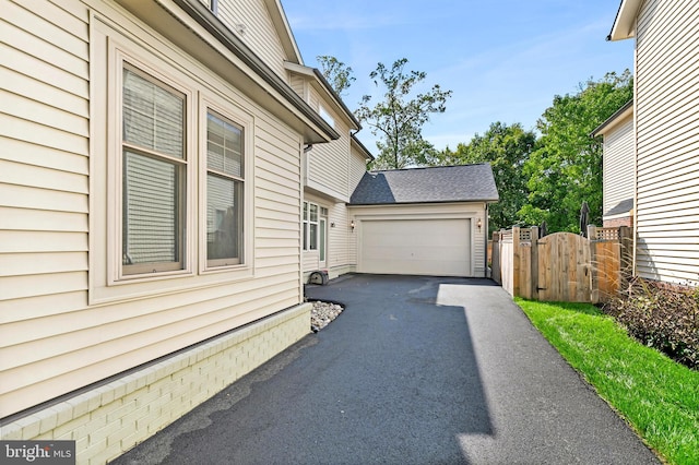 view of home's exterior featuring a garage, a gate, and fence