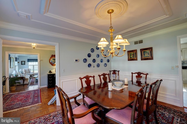 dining area featuring a tray ceiling, wainscoting, visible vents, and a notable chandelier