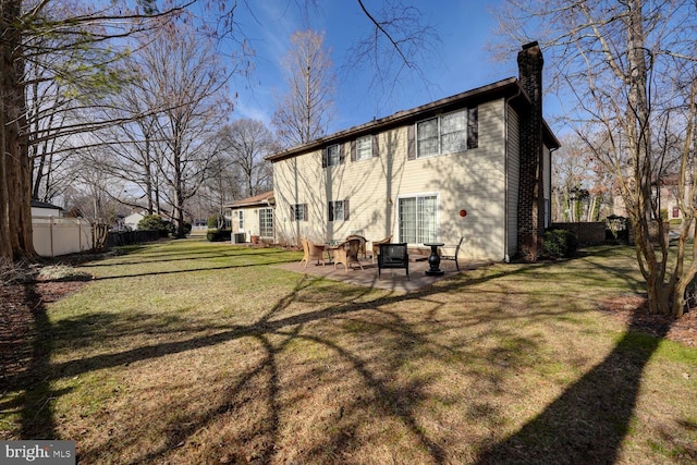 back of house featuring a chimney, fence, a lawn, and a patio