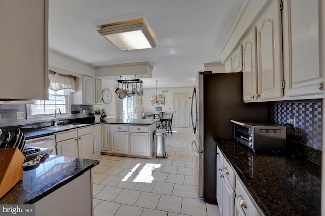 kitchen featuring tasteful backsplash, a sink, a peninsula, and light tile patterned floors