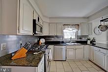 kitchen with a sink, stainless steel appliances, dark countertops, and backsplash