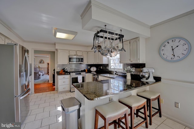 kitchen with stainless steel appliances, a peninsula, a sink, ornamental molding, and tasteful backsplash