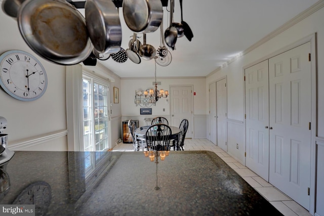 dining space with a chandelier, wainscoting, ornamental molding, and light tile patterned floors