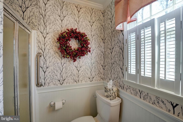 bathroom with a wealth of natural light, a wainscoted wall, toilet, and wallpapered walls