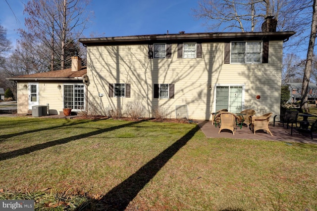 rear view of house with a patio area, a yard, a chimney, and central AC unit