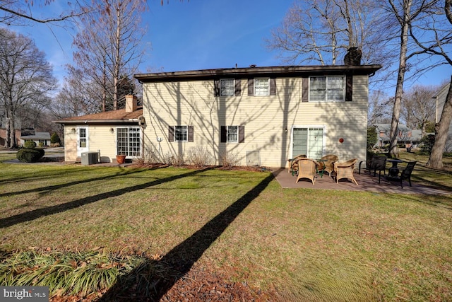 rear view of property featuring a patio area, a chimney, a lawn, and central AC