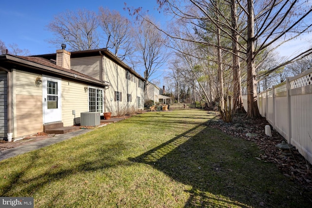 view of yard featuring central air condition unit, a fenced backyard, and entry steps