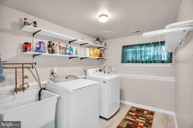 laundry area with laundry area, a sink, visible vents, light wood-type flooring, and washing machine and clothes dryer