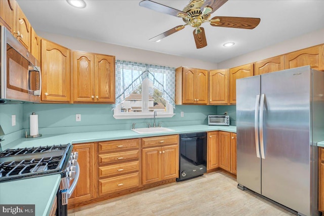 kitchen featuring a ceiling fan, light wood-style flooring, stainless steel appliances, light countertops, and a sink