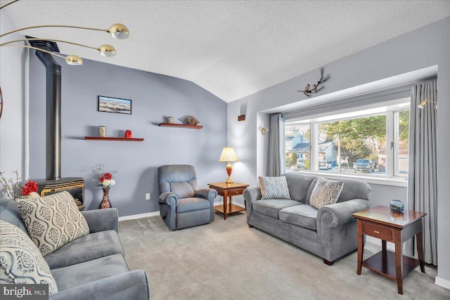 living room featuring lofted ceiling, a wood stove, carpet flooring, a textured ceiling, and baseboards