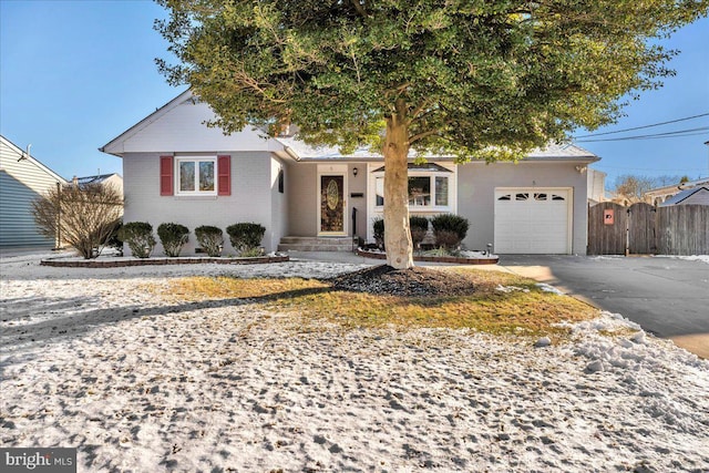 single story home with driveway, brick siding, an attached garage, and fence