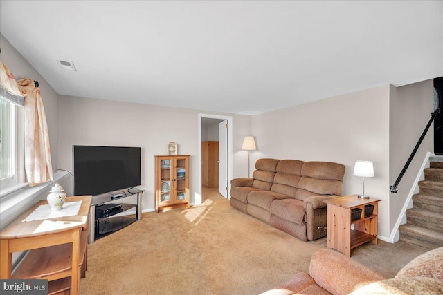 carpeted living area with stairs, visible vents, and baseboards