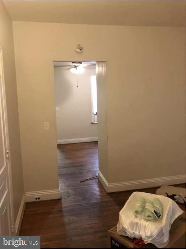 hallway with dark wood-style flooring and baseboards