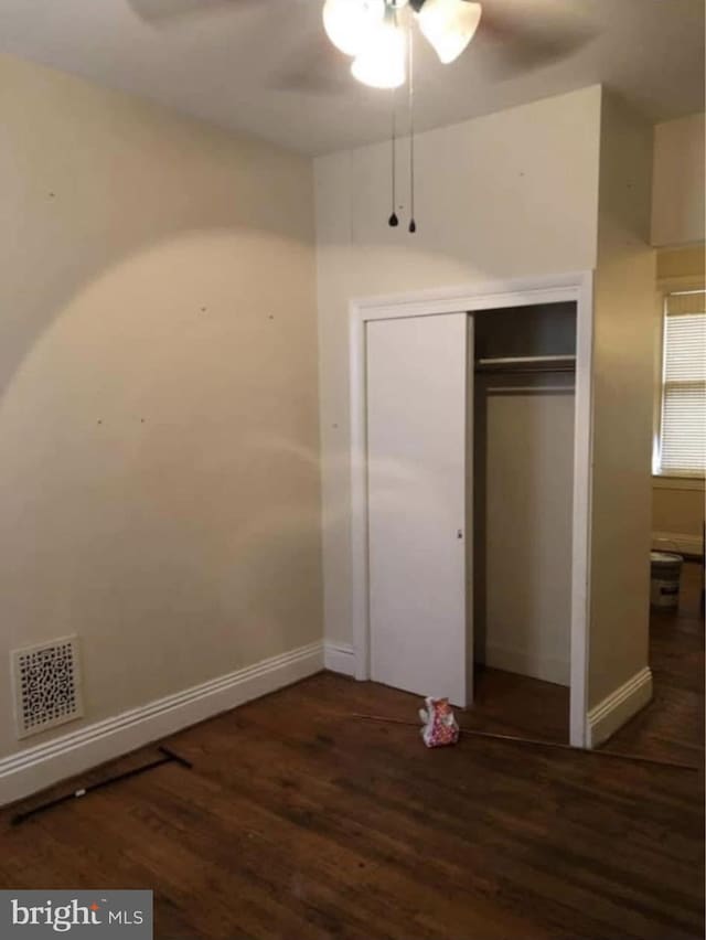 unfurnished bedroom with baseboards, a closet, visible vents, and wood finished floors