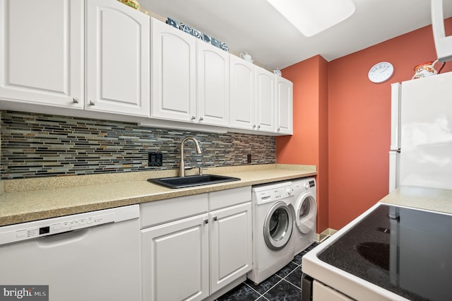 clothes washing area with laundry area, separate washer and dryer, a sink, and dark tile patterned flooring