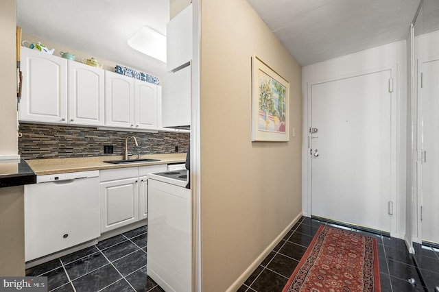 doorway to outside featuring washer / dryer, baseboards, a sink, and dark tile patterned flooring