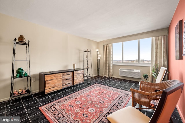 living area featuring dark tile patterned flooring, a wall unit AC, and baseboards