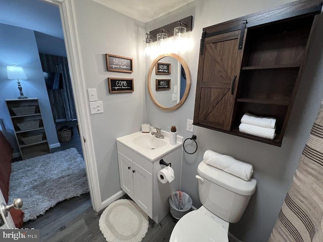 bathroom with toilet, baseboards, wood finished floors, and vanity