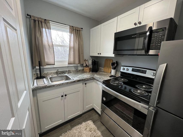 kitchen featuring appliances with stainless steel finishes, a sink, and white cabinets