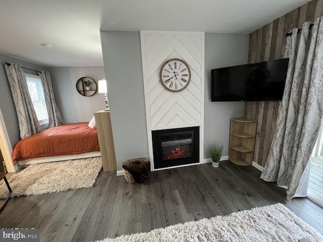 bedroom with a large fireplace, baseboards, and wood finished floors