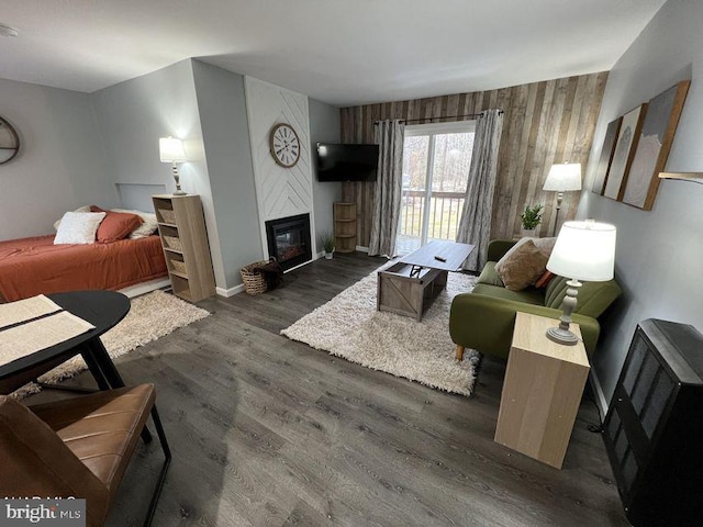 living area featuring wooden walls, a fireplace, baseboards, and wood finished floors