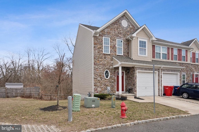 view of front facade featuring concrete driveway, an attached garage, fence, and stone siding