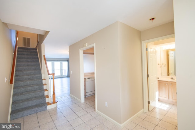 hall with visible vents, stairway, baseboards, and light tile patterned floors