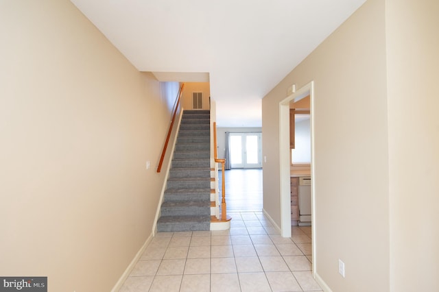 staircase featuring baseboards, visible vents, and tile patterned floors