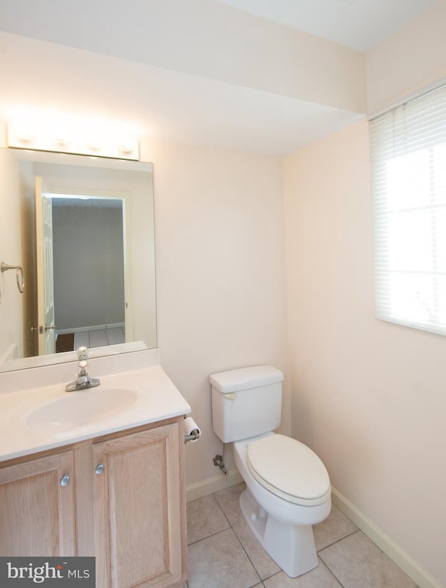 bathroom with toilet, vanity, baseboards, and tile patterned floors