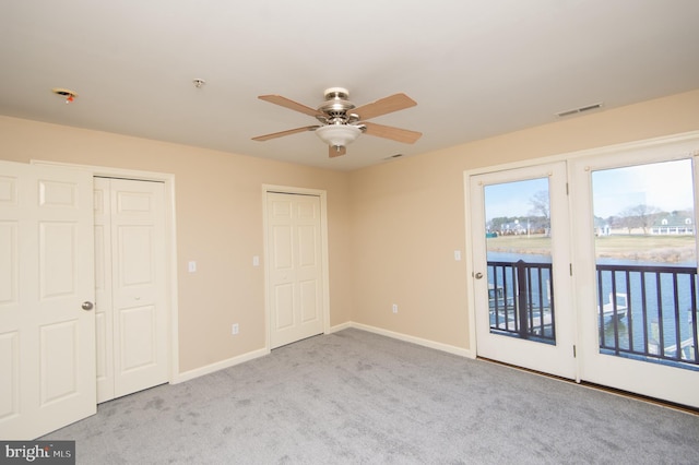 unfurnished bedroom featuring carpet floors, visible vents, multiple closets, access to exterior, and multiple windows