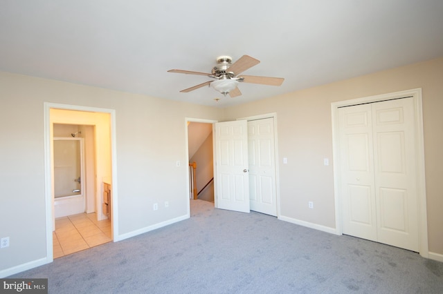 unfurnished bedroom with carpet floors, two closets, and baseboards